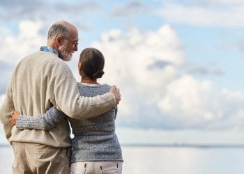 an older couple smuggling outside looking at the sea