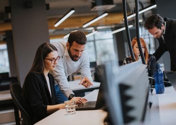 emberek egy asztalnal dolgoznak szamitogepeken